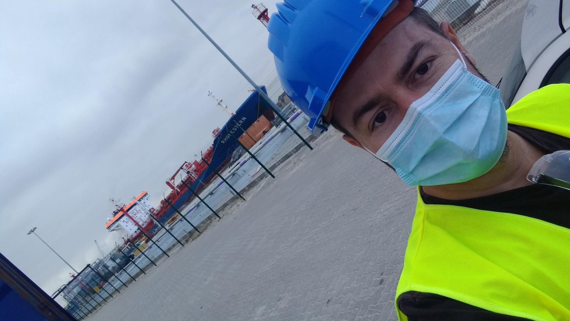 Autor em ambiente de trabalho portuário com equipamento de segurança, simbolizando persistência.
